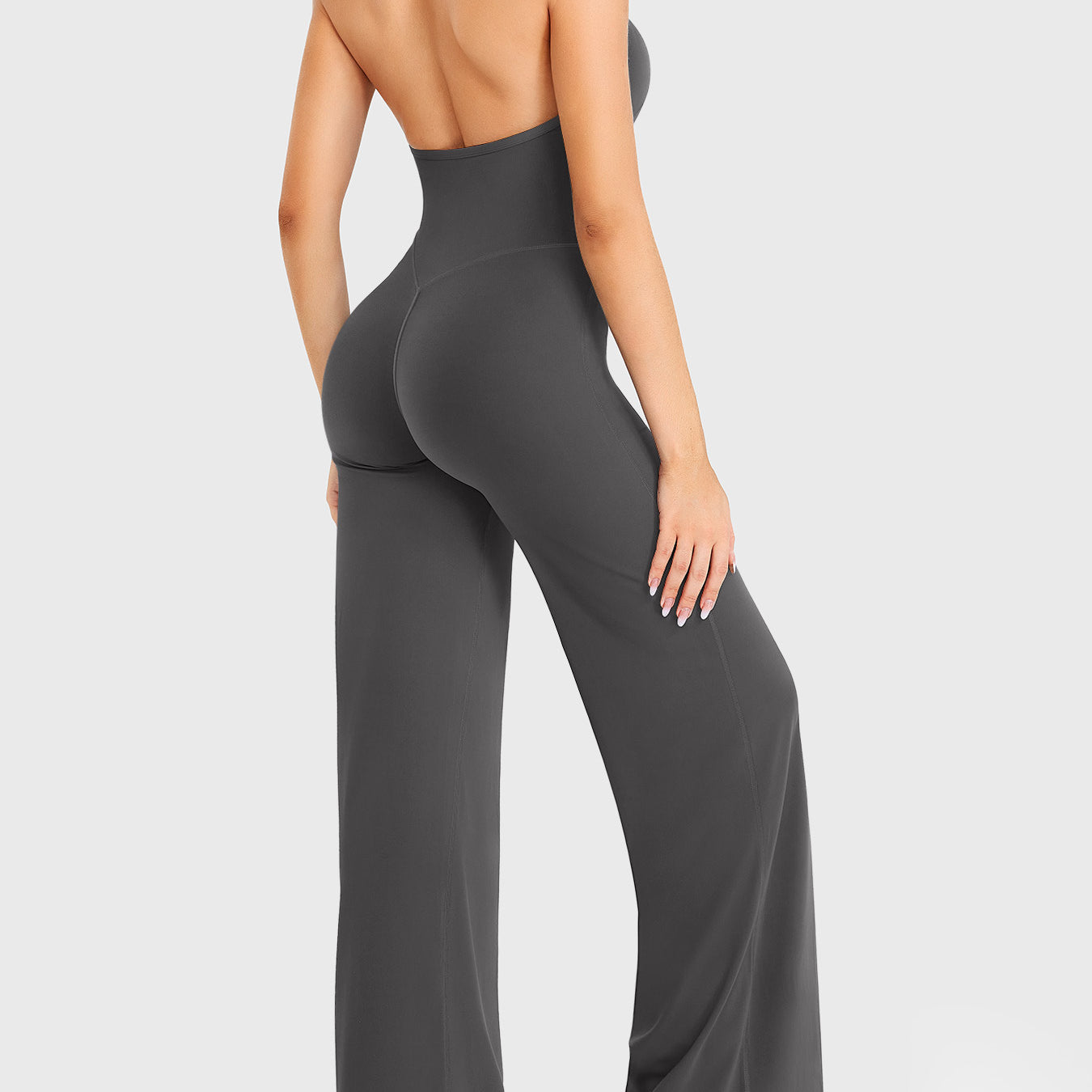 Side-front stretch pose wearing dark grey halter straight-leg jumpsuit
