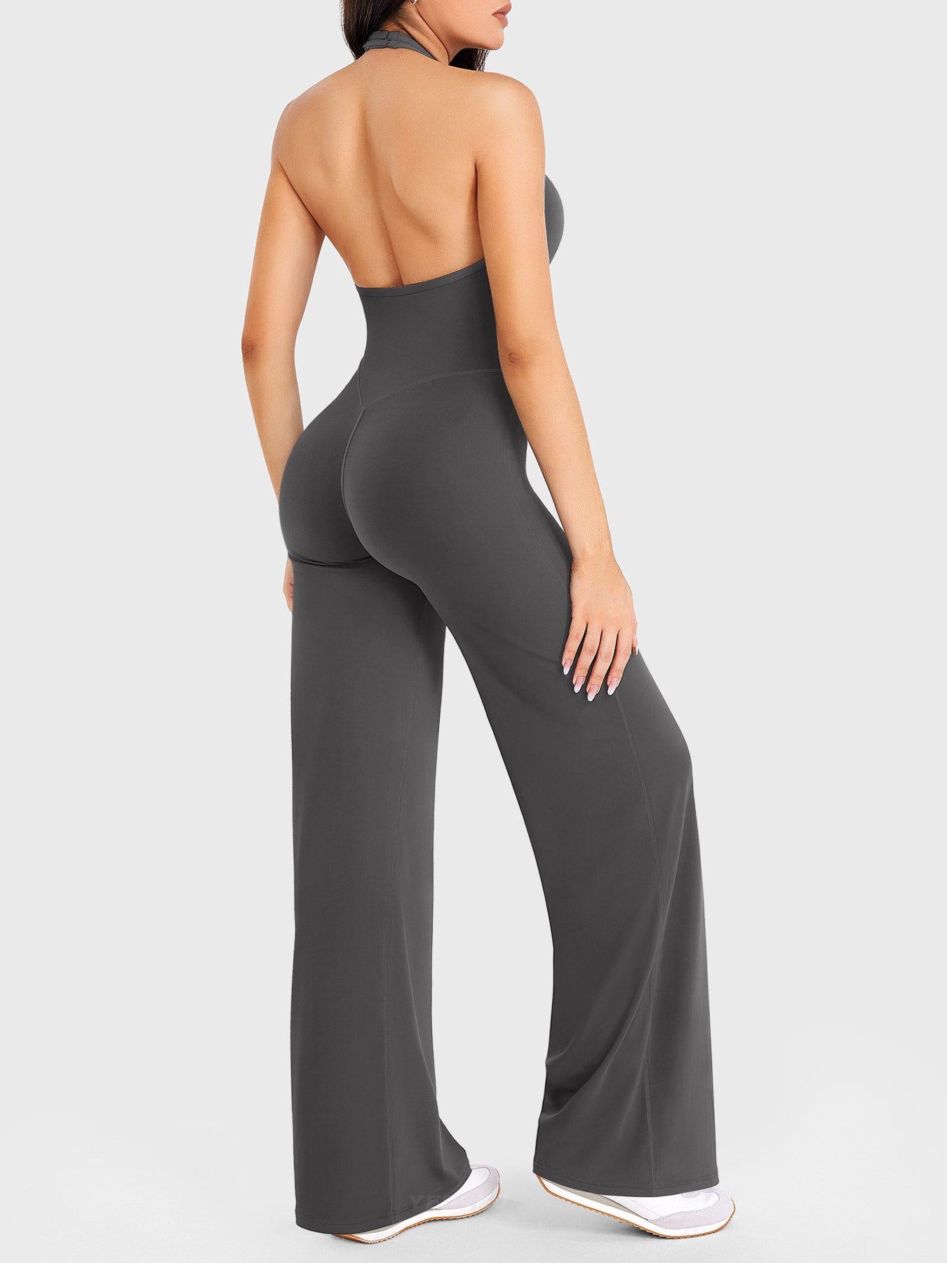 Side-front stretch pose wearing dark grey halter straight-leg jumpsuit