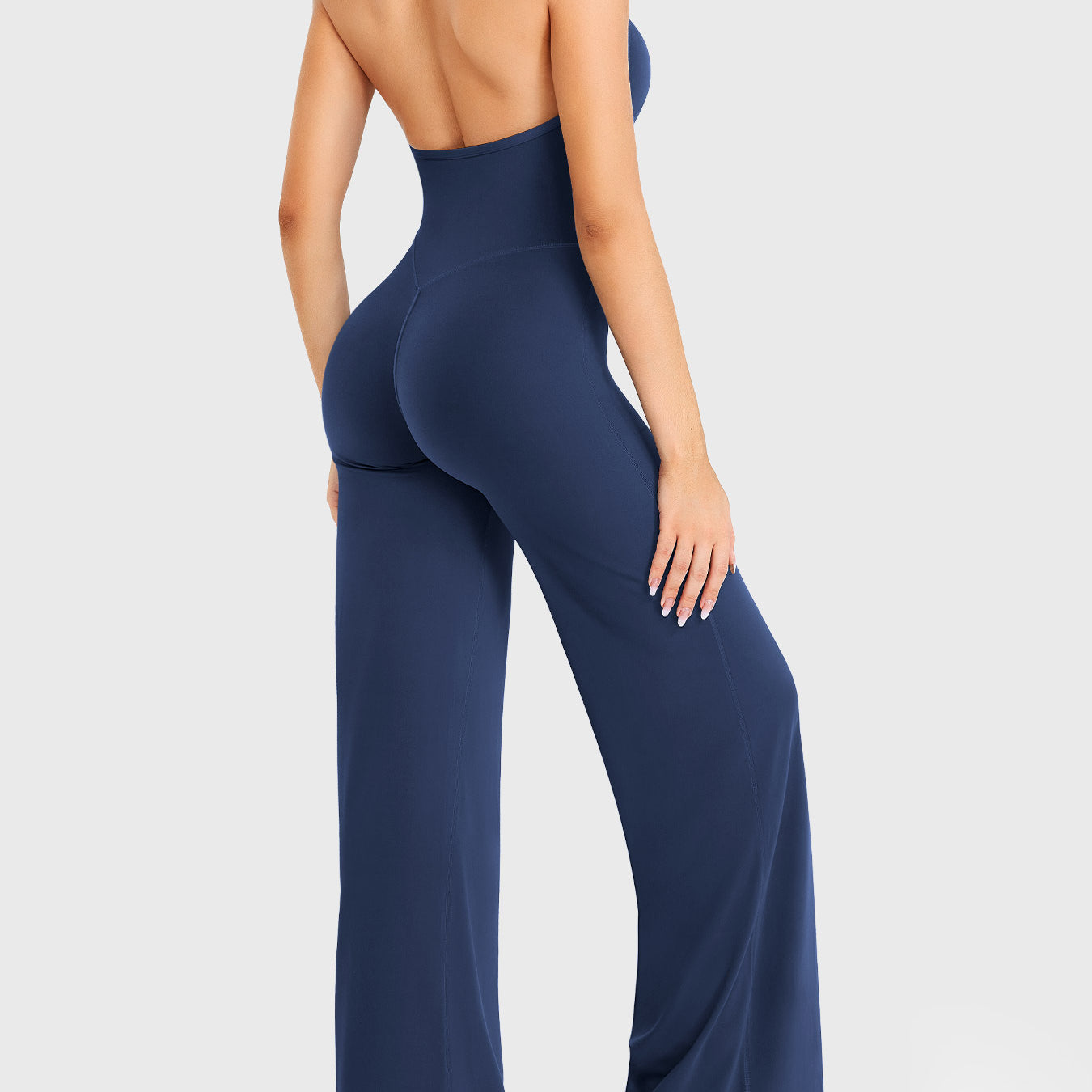 Side-front stretch pose wearing navy halter straight-leg jumpsuit