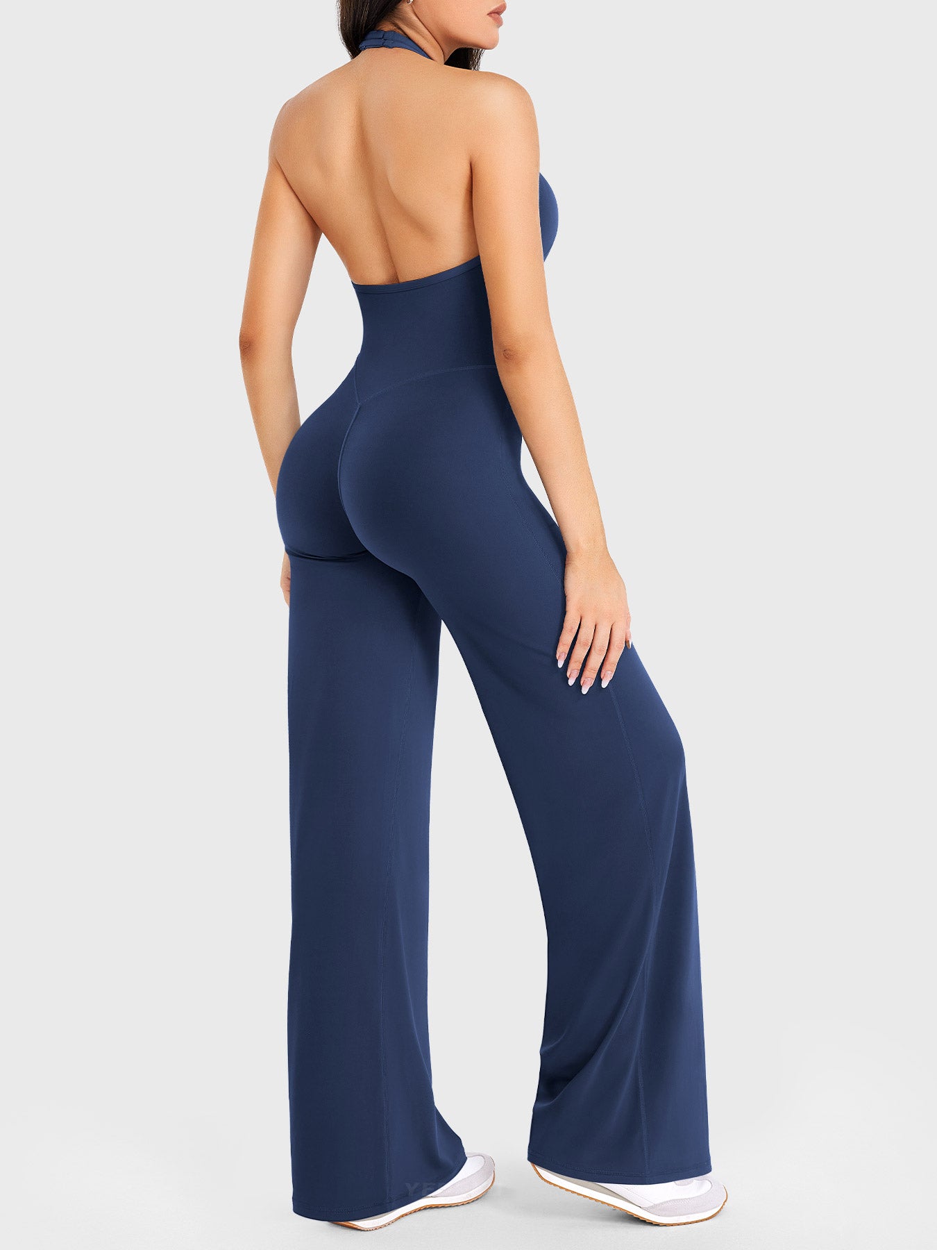 Side-front stretch pose wearing navy halter straight-leg jumpsuit