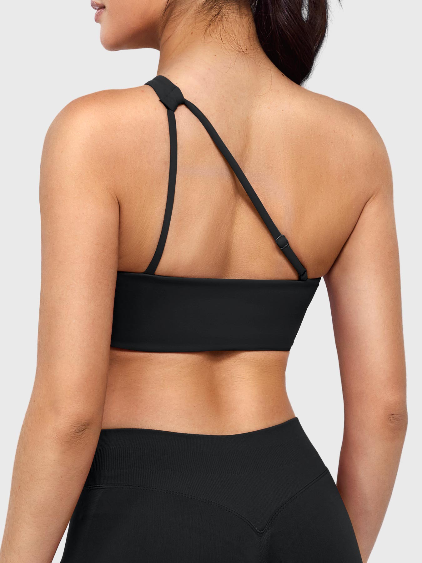 Claranie One Shoulder Sports Bra in black, angled back view upper body, open back with adjustable strap, breathable design