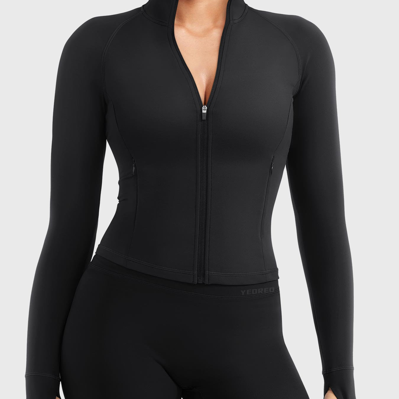 Candecy Full Zip Workout Jacket in black, front view standing, partially unzipped V neckline, princess seams, hidden zip pockets, thumbhole cuffs