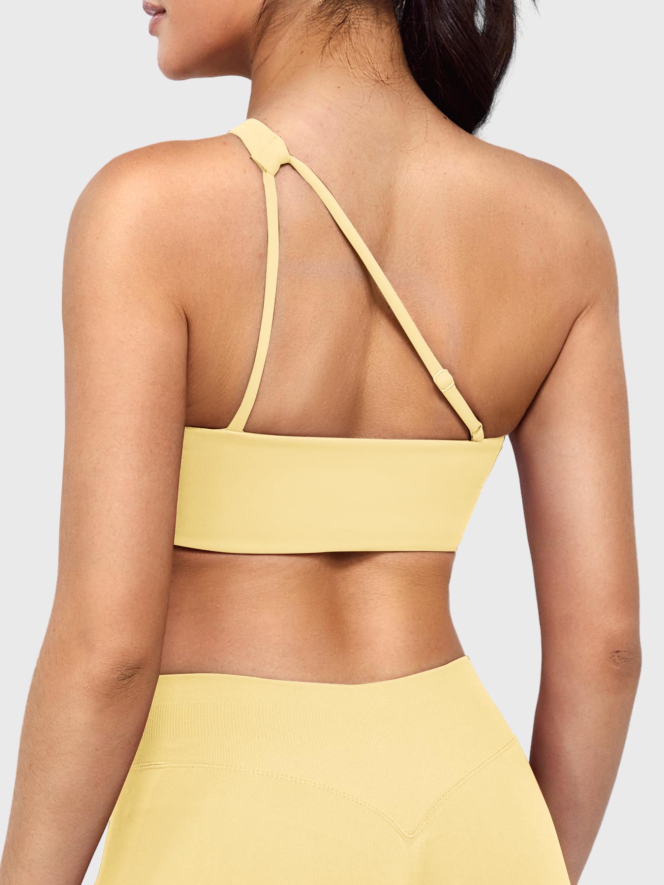 Claranie One Shoulder Sports Bra in milk yellow, angled back view upper body, open back design with adjustable strap, breathable fit