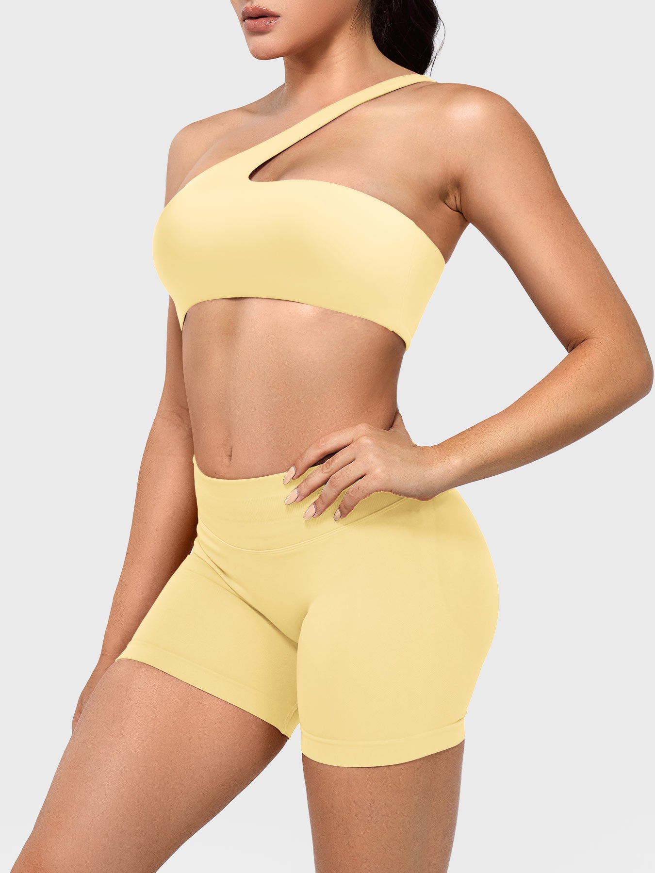 Claranie One Shoulder Sports Bra in milk yellow, angled front upper body view styled with shorts, smooth body-hugging fit