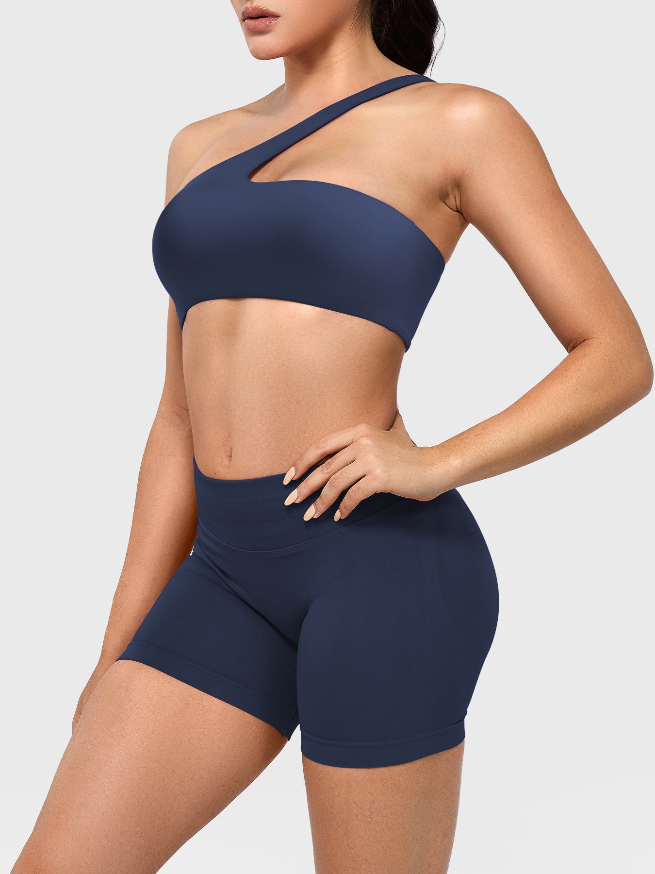Claranie One Shoulder Sports Bra in navy, angled front upper body view styled with shorts, fitted athletic look highlighting curves