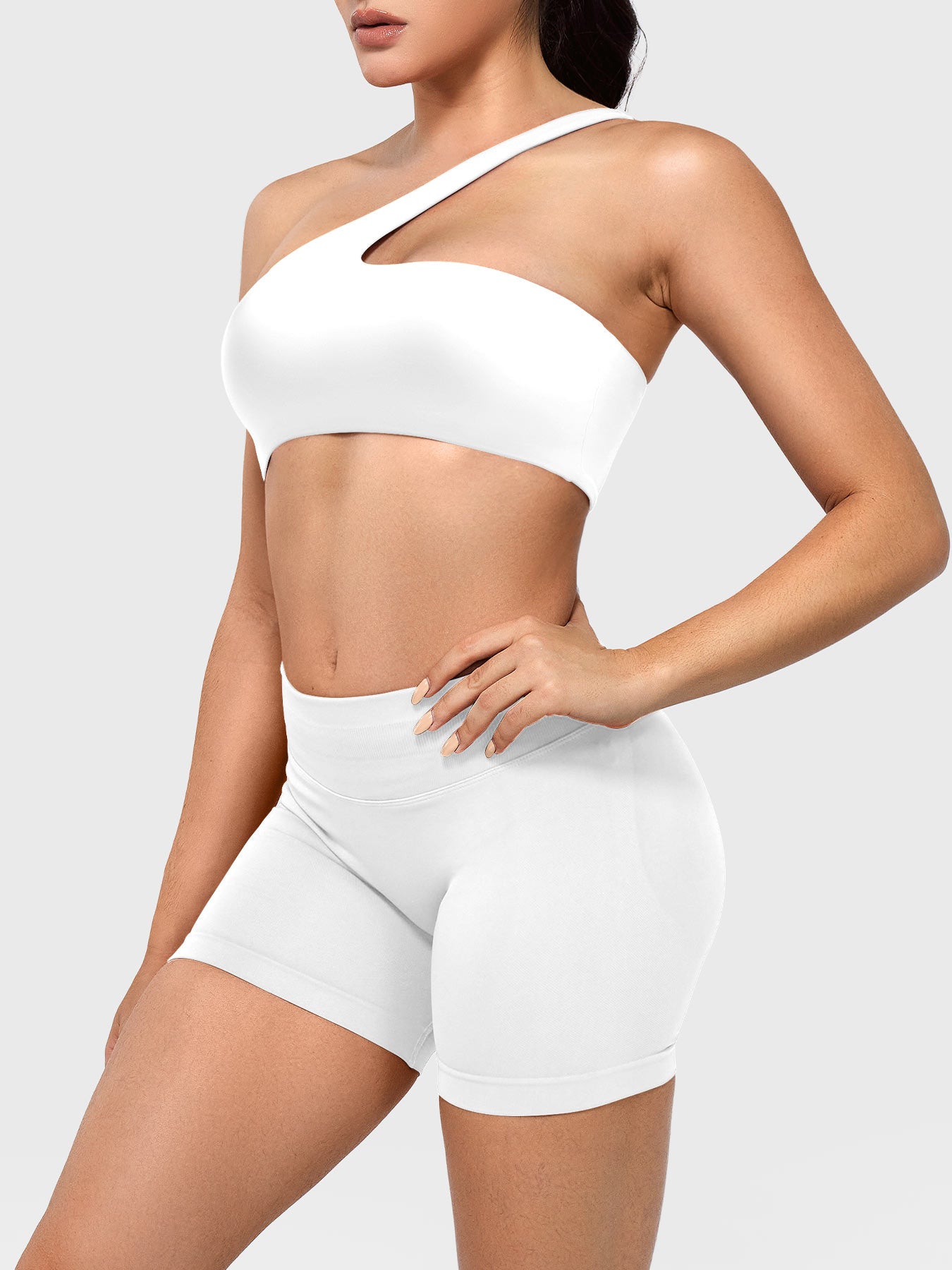 Claranie One Shoulder Sports Bra in white, angled front upper body view styled with shorts, smooth body-hugging fit