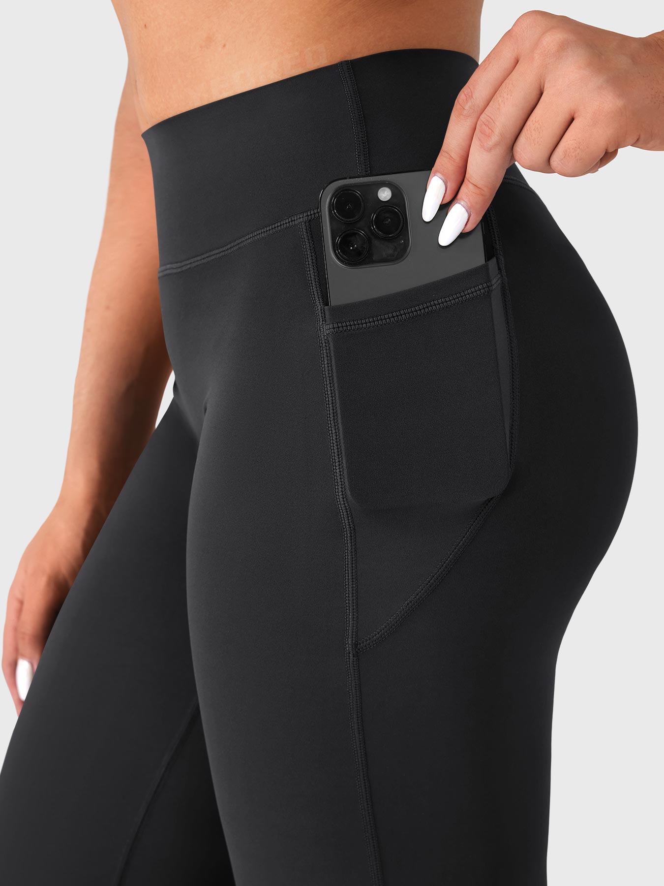 Close-up of black straight leg leggings side pocket with phone, practical athleisure design