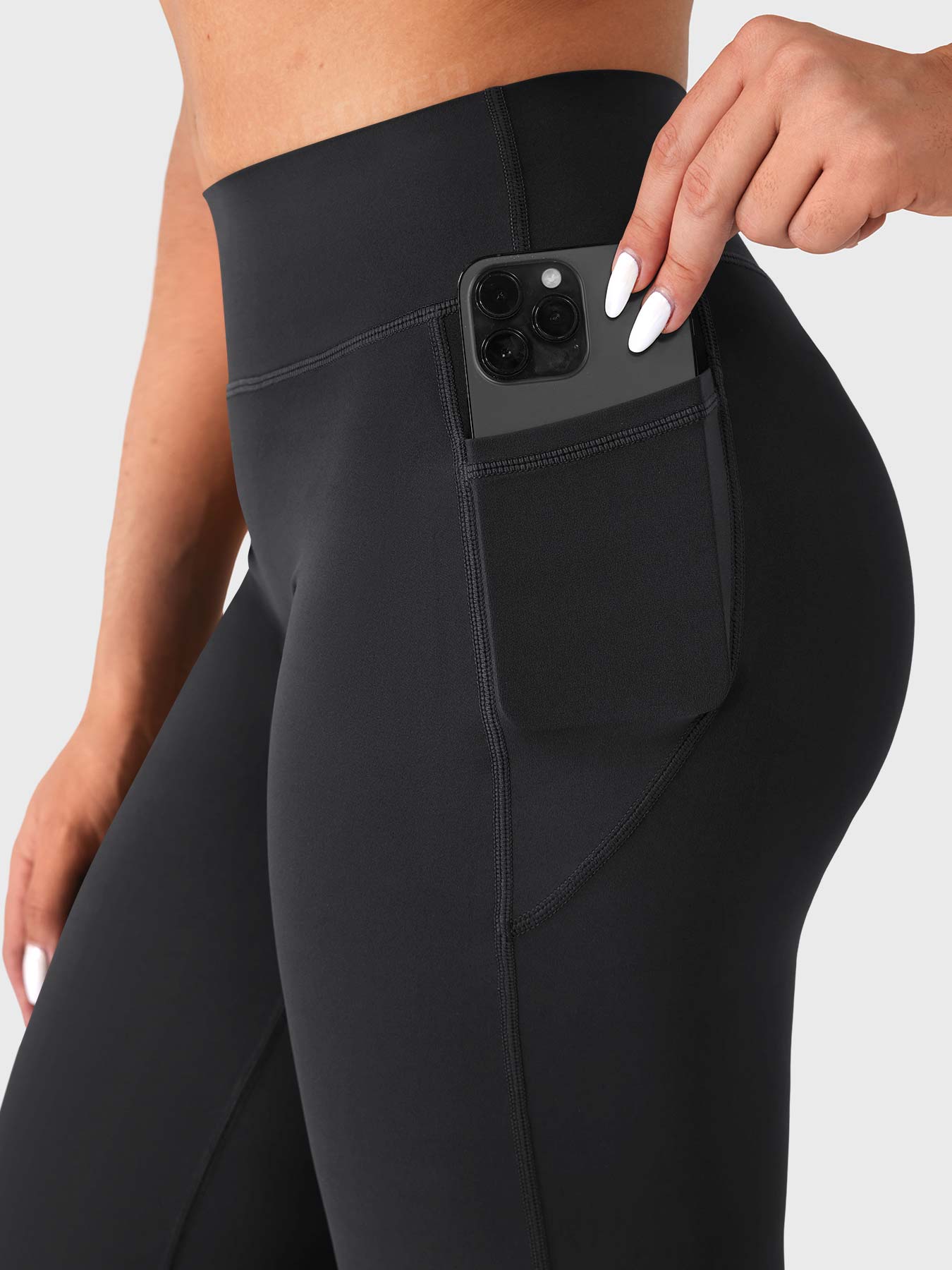 Black straight leg leggings with side pockets holding phone, everyday athleisure essential