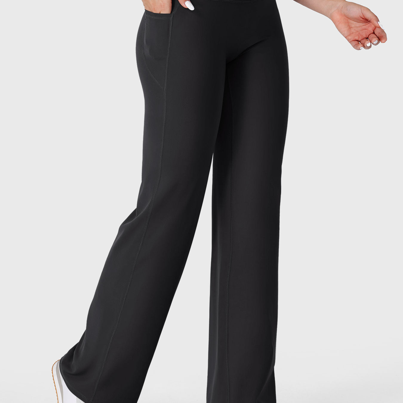 Black straight straight leg leggings with pockets walking front angle, hands in pockets