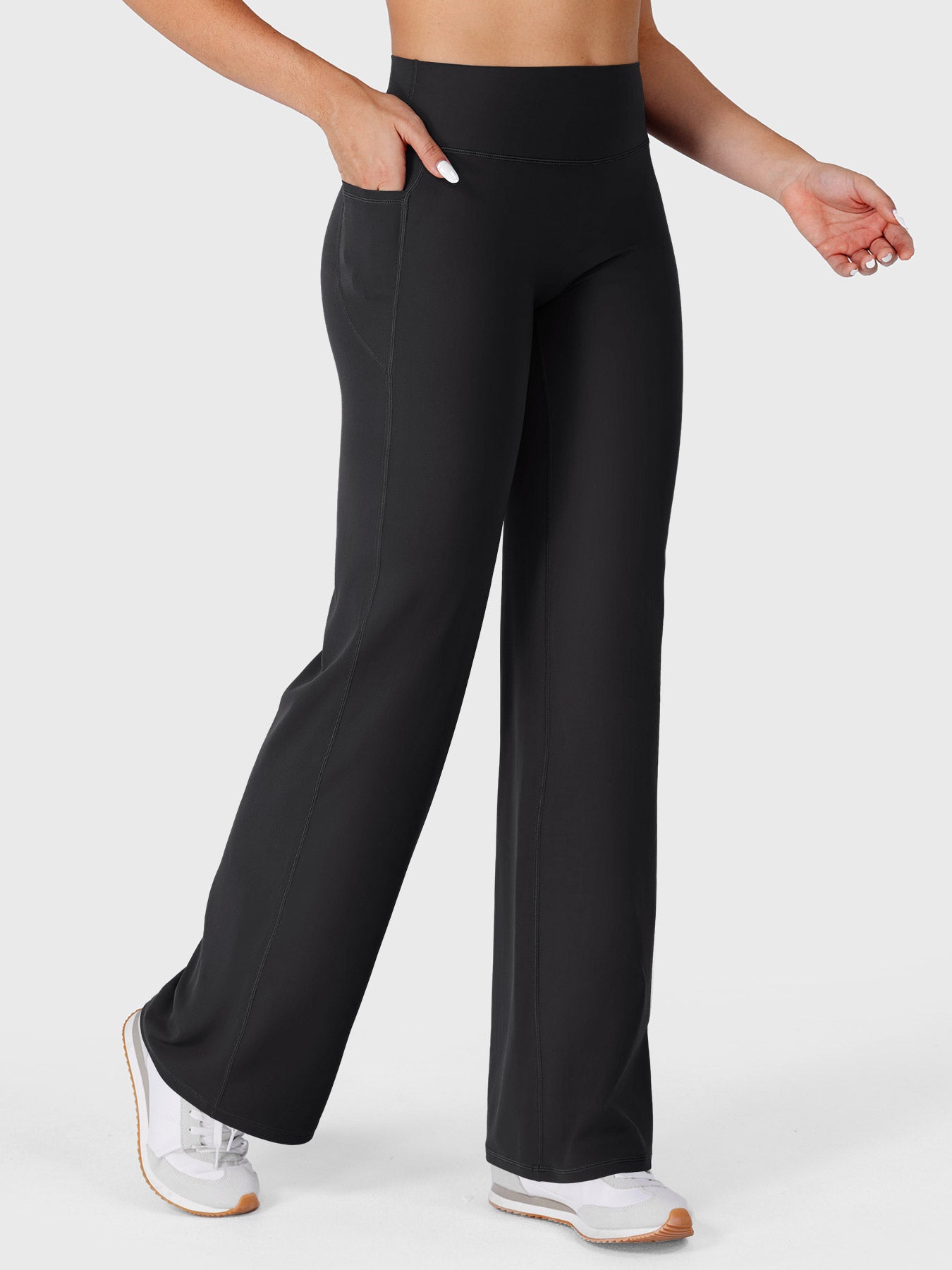 Black straight straight leg leggings with pockets walking front angle, hands in pockets