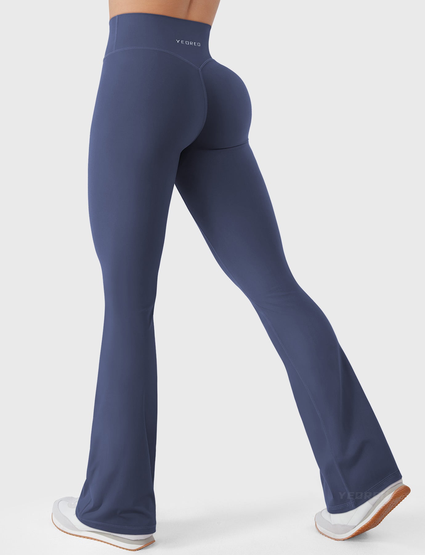 Navy bootcut mini flare leggings with V-back and hidden scrunch, side-back walking pose