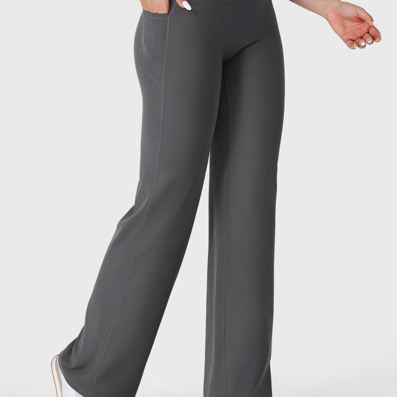 Dark grey straight leg leggings with pockets walking front angle, hands in pockets