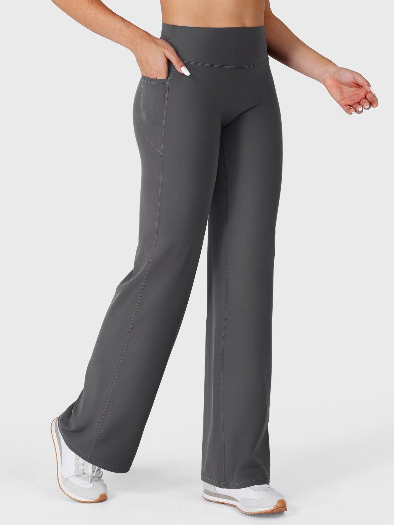 Dark grey straight leg leggings with pockets walking front angle, hands in pockets