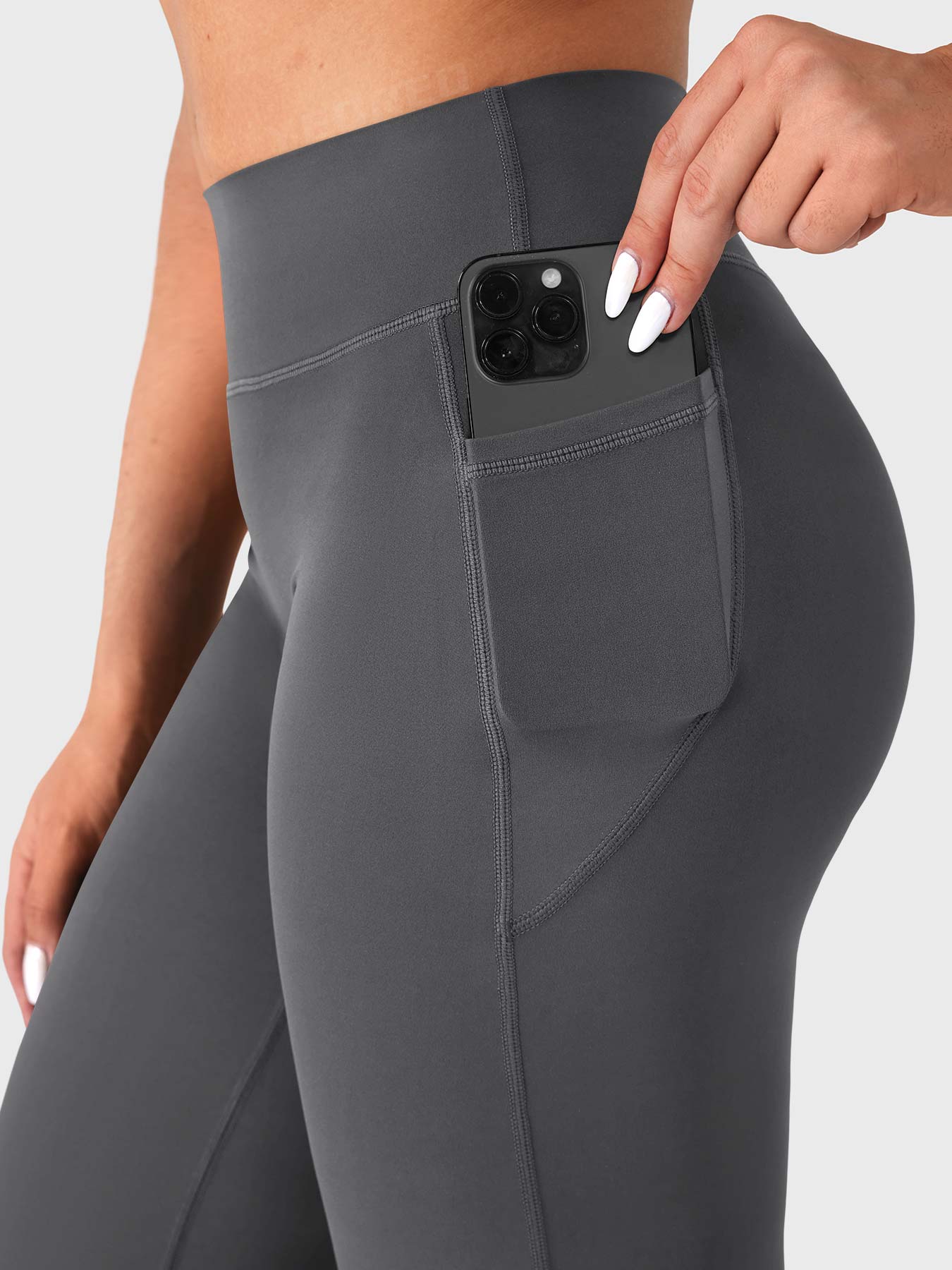 Close-up of dark grey straight leg leggings side pocket holding phone, functional design