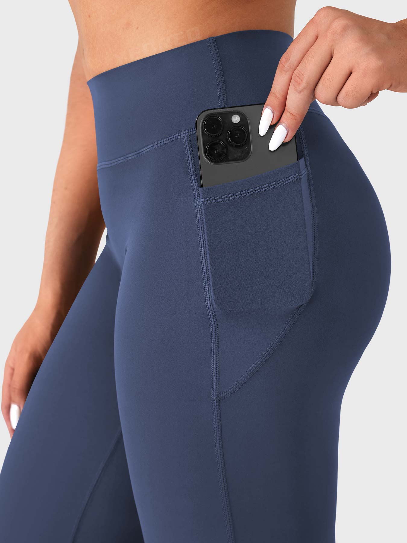 Close-up of navy straight leg leggings side pocket holding phone, no front seam design