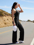 Outdoor sunlight—side-front angle shot of model wearing black straight-leg halter jumpsuit