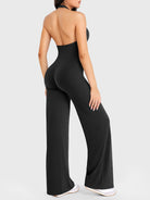 Side-front stretch pose wearing black halter straight-leg jumpsuit