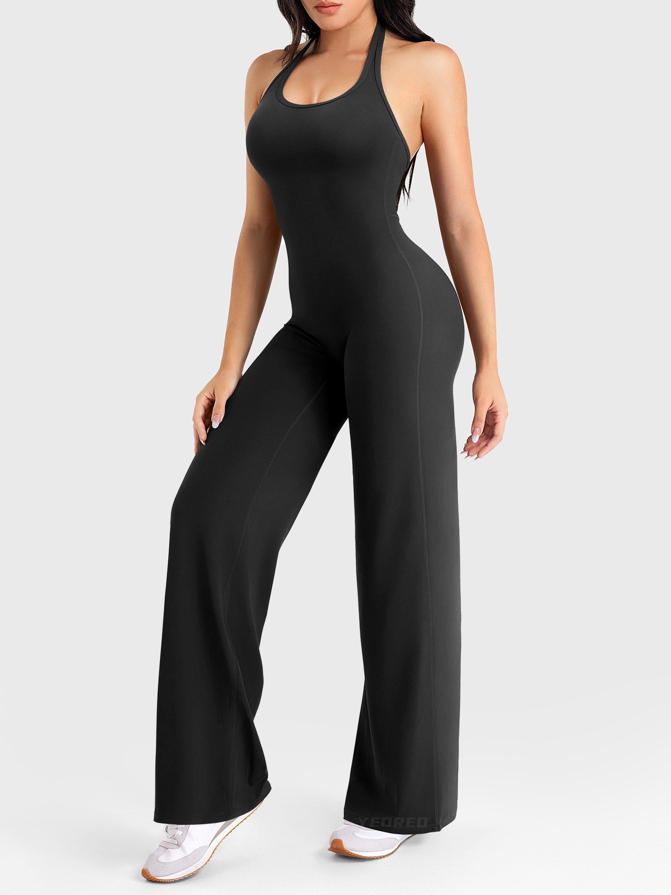 Side-front stretch pose wearing black halter straight-leg jumpsuit