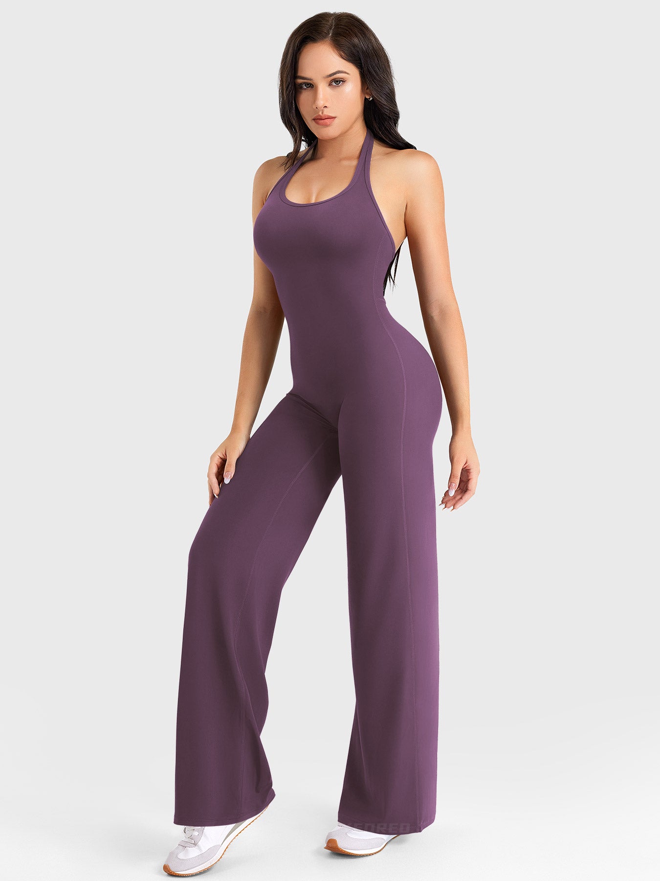 Back-angle stretch pose showing hidden-scrunch booty lift in black berry halter jumpsuit