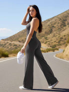 Outdoor sunlight—model walking side view in dark grey straight-leg halter jumpsuit