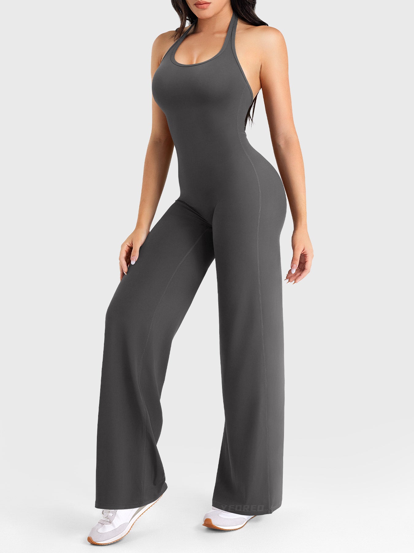 Side-front stretch pose wearing dark grey halter straight-leg jumpsuit