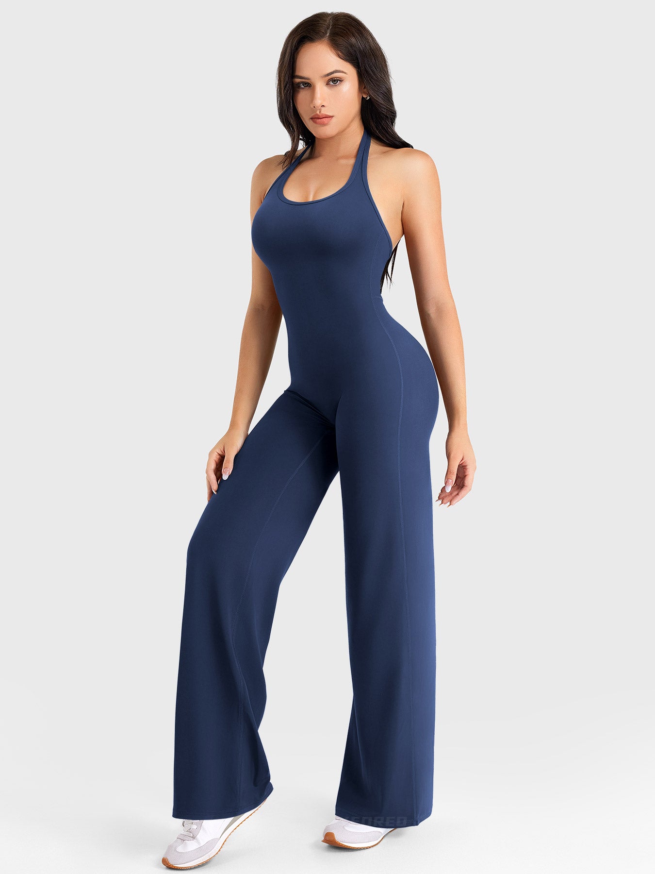 Side-front stretch pose wearing navy halter straight-leg jumpsuit
