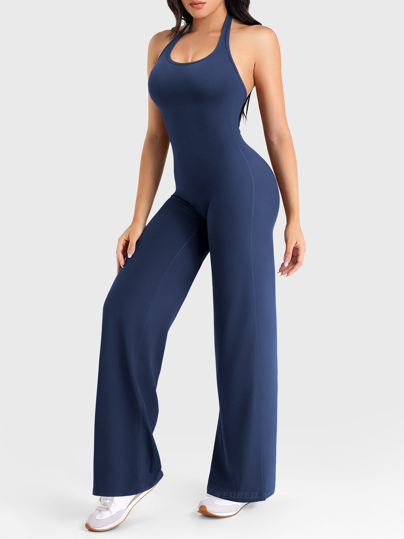 Side-front stretch pose wearing navy halter straight-leg jumpsuit