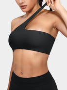 Claranie One Shoulder Sports Bra in black, angled front upper body view, elastic shoulder strap stretch detail
