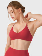Maroon Yeoreo Zaahira V-neck sports bra angled front view, stretch shoulder strap demonstrating flexibility