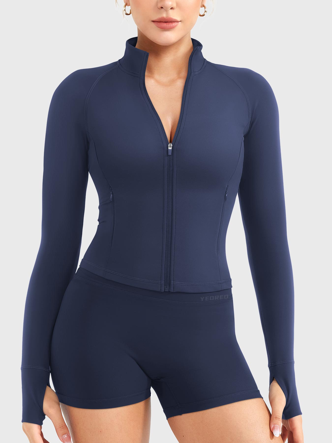 Candecy Full Zip Workout Jacket in navy, front standing view, partially unzipped V neckline, princess seam shaping, thumbhole cuffs