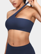 Claranie One Shoulder Sports Bra in navy, angled front upper body view, elastic shoulder strap stretch detail