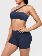 Claranie One Shoulder Sports Bra in navy, angled front upper body view styled with shorts, fitted athletic look highlighting curves