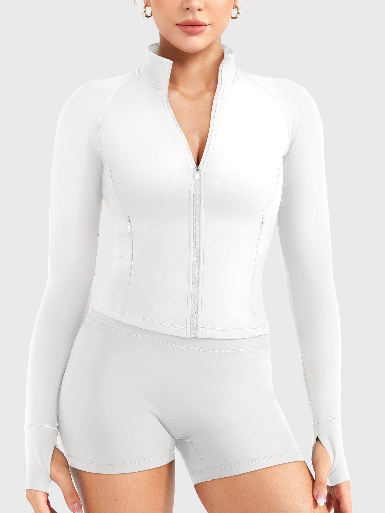 Candecy Full Zip Workout Jacket in white, front standing view, partially unzipped V neckline, princess seam tailoring, thumbhole cuffs