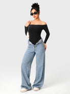 Dacrly Off Shoulder Bodysuit in black, full body front view layered with jeans, styled with sunglasses and shoulder bag, Y2K streetwear outfit